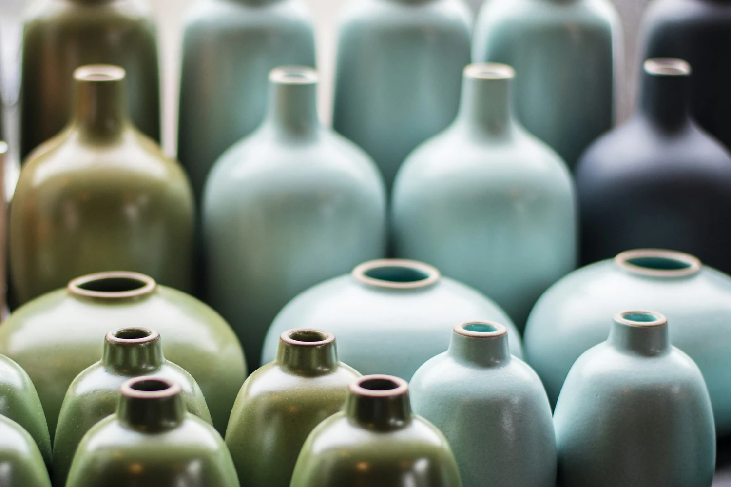 Rząd butelek ceramicznych w zielonych i błękitnych szkliwach