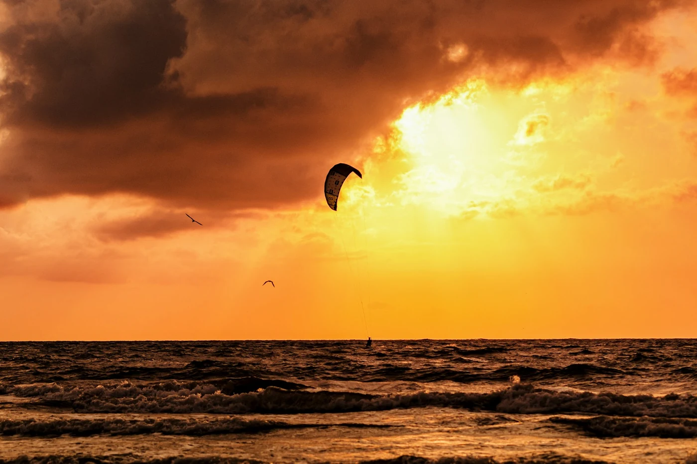 Un kite recortado contra un cielo naranja al atardecer sobre el mar