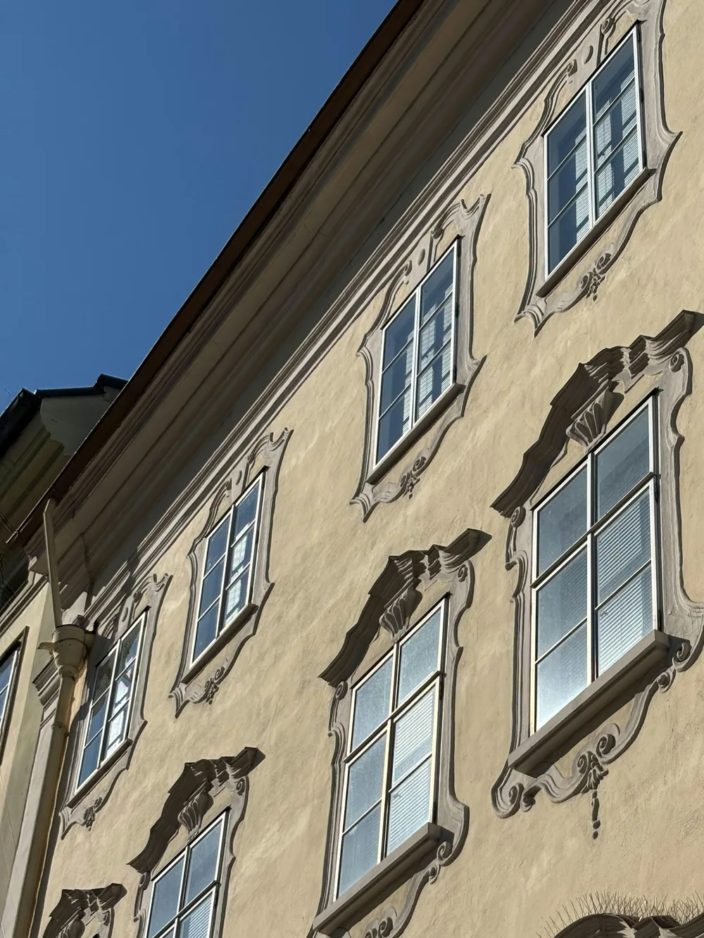 Helle Fassade eines alten Hauses mit Stuckrahmen um die Fenster