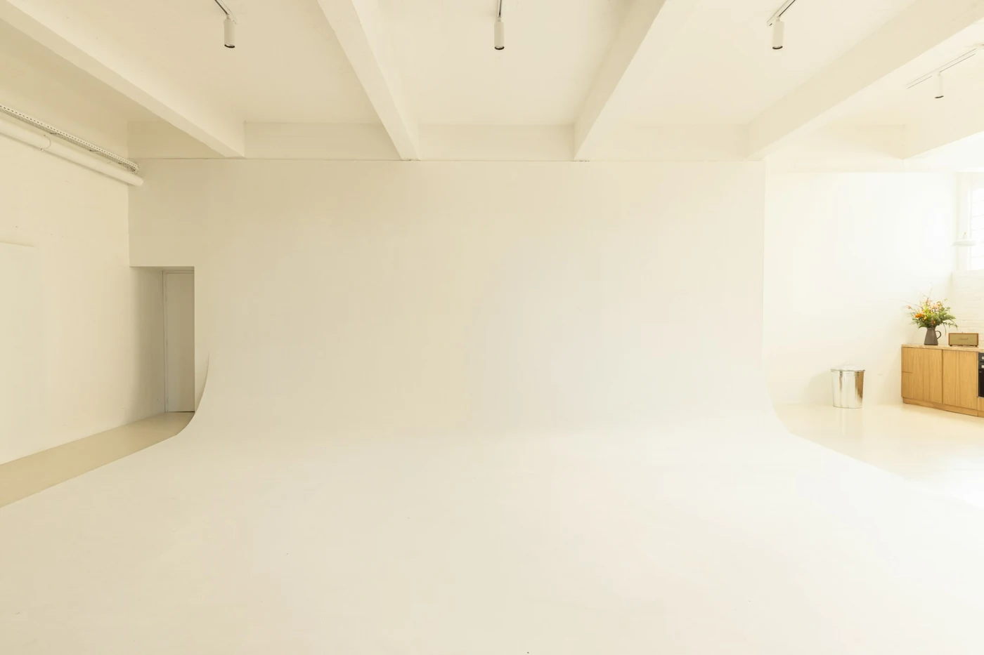 Pusta sala z białą cykloramą bez szwów i belkami pod sufitem