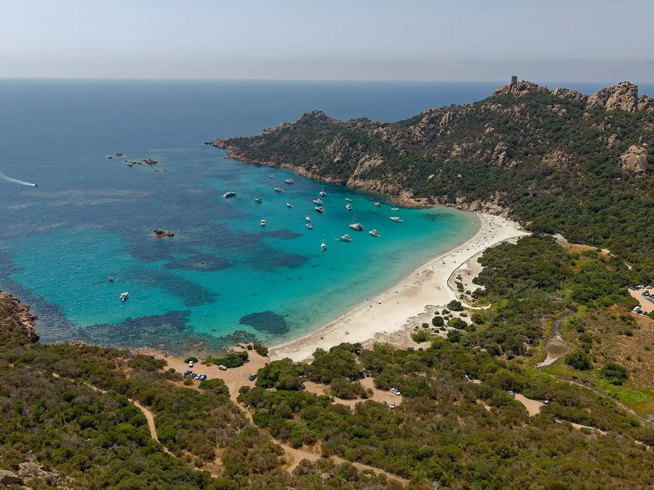 Aerial view of a turquoise bay with boats anchored off a sandy beach